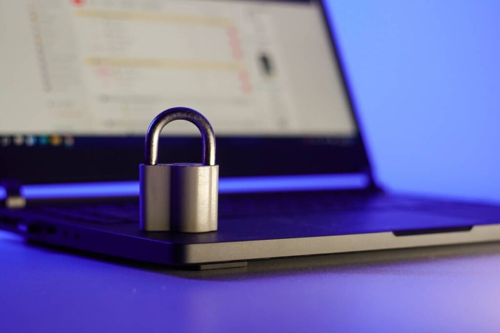 Locked metal padlock on a laptop keyboard over blue background. Cyber security concept
