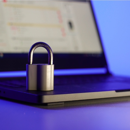 Locked metal padlock on a laptop keyboard over blue background. Cyber security concept.