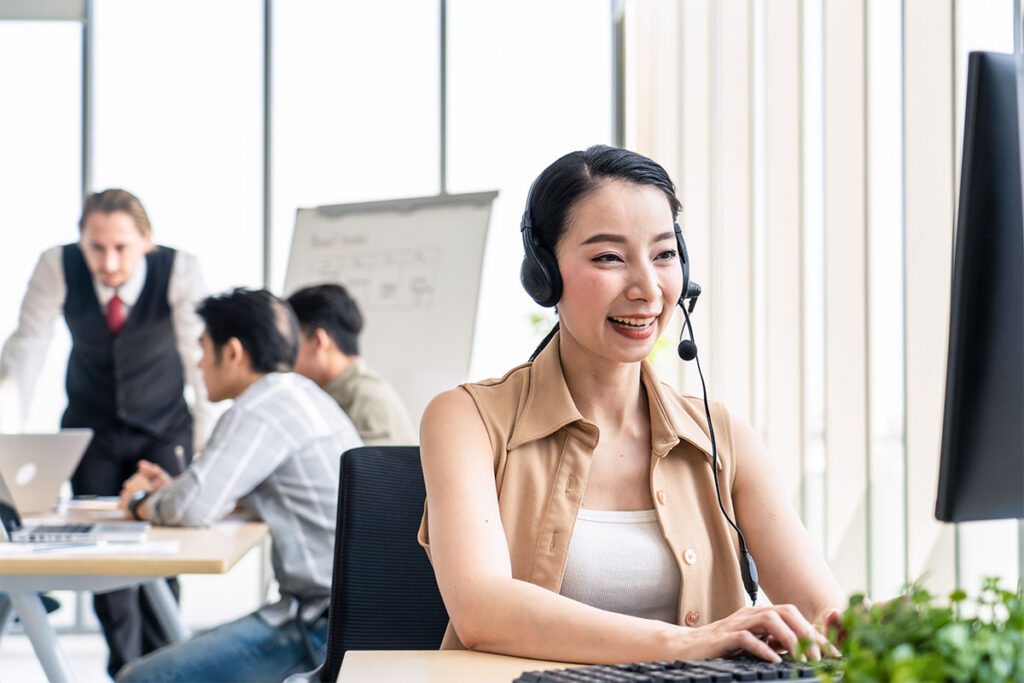 Asian young call center work with smile in workplace while colleague meeting and brainstorming