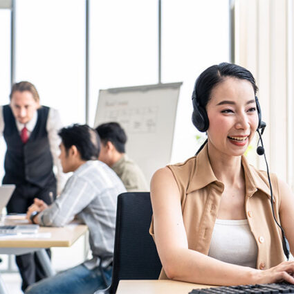 Asian young call center work with smile in workplace while colleague meeting and brainstorming