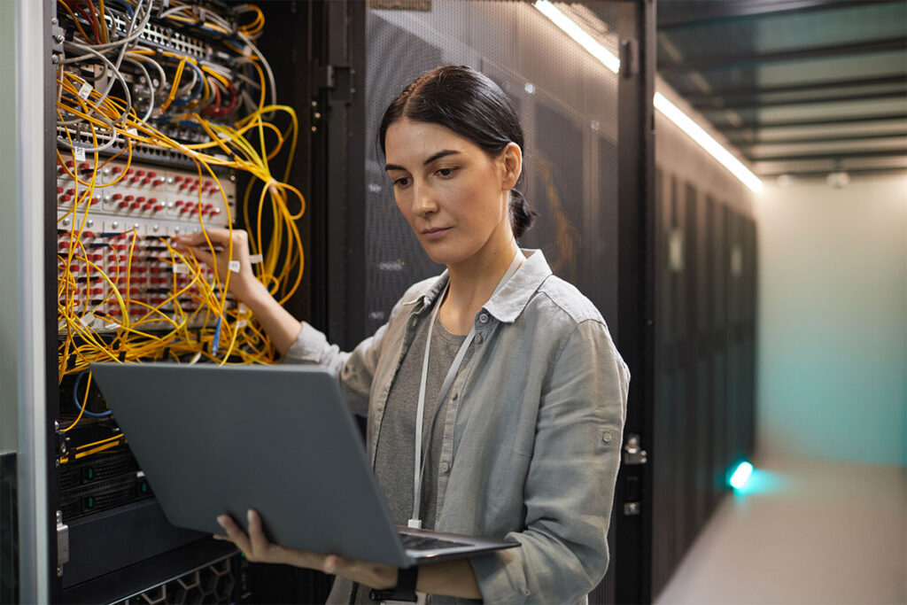 Female Network Technician Inspecting Servers in Data Center - featured
