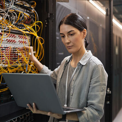 Female Network Technician Inspecting Servers in Data Center