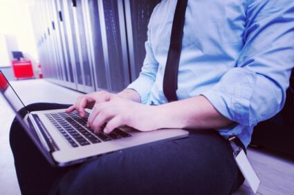 Male IT engineer working on a laptop in server room at modern data center